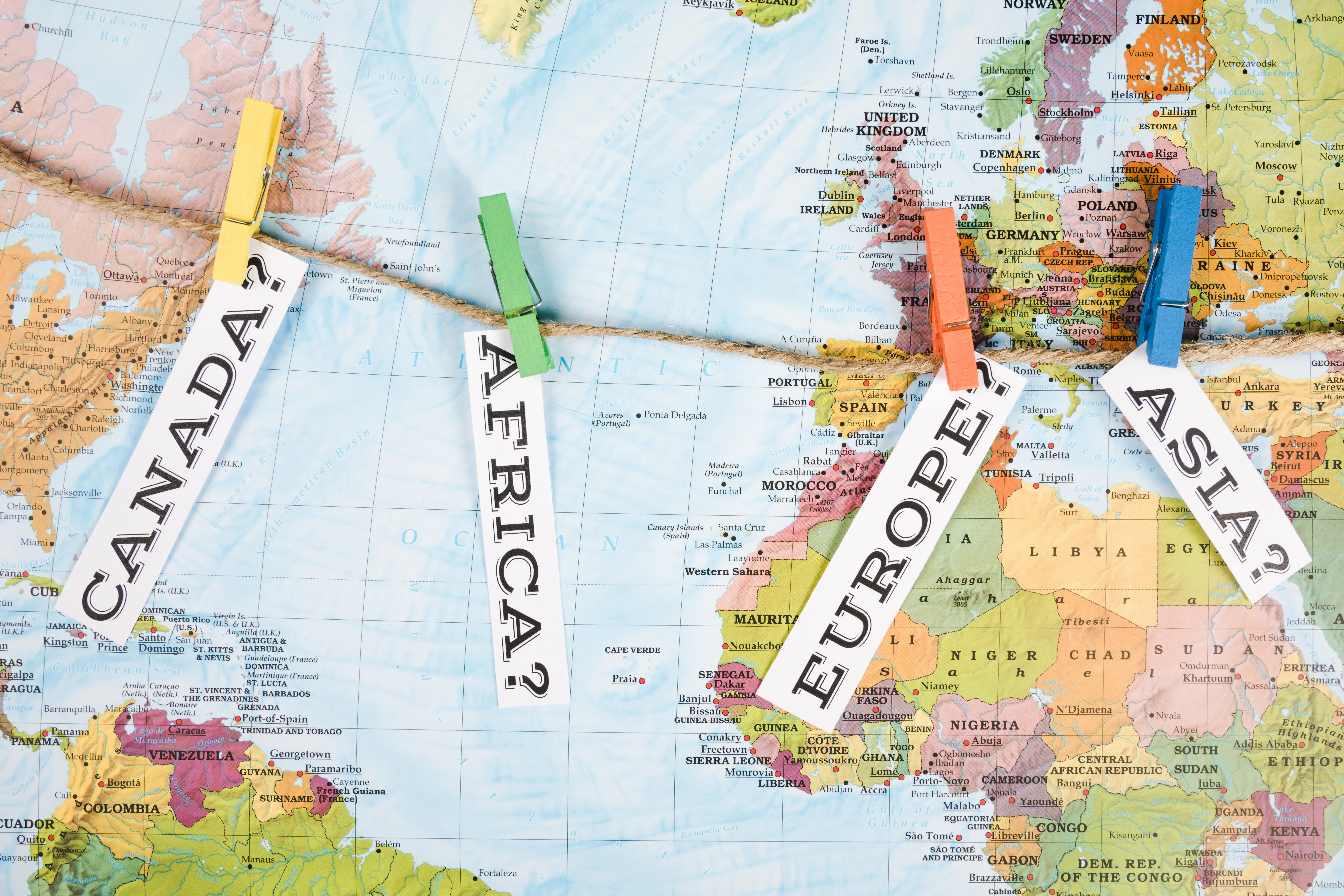 Overhead view of different continent name tags with clothes pegs on a map