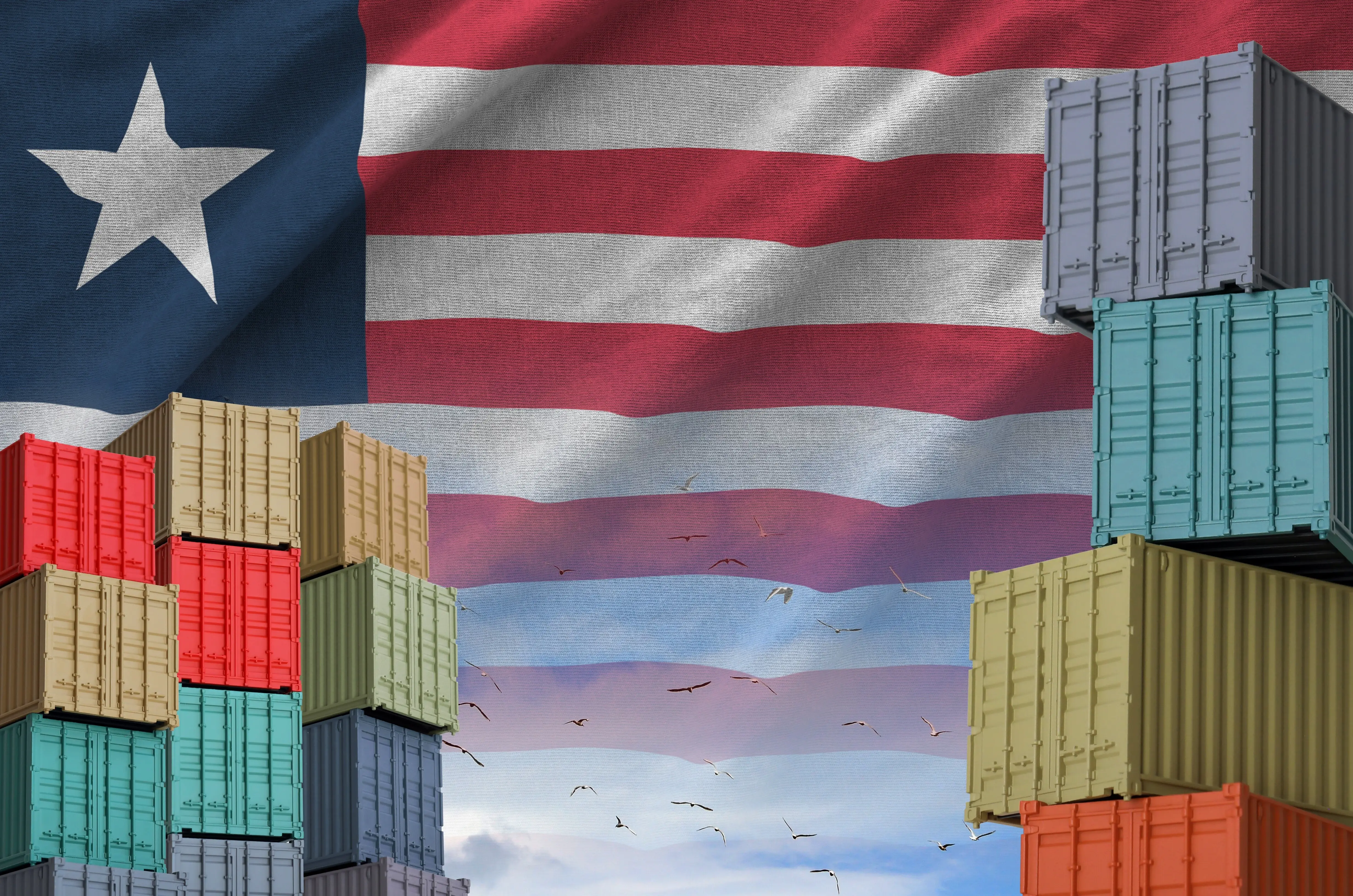 Liberian flag and a large stack of shipping cargo containers at the docks with a sky background.